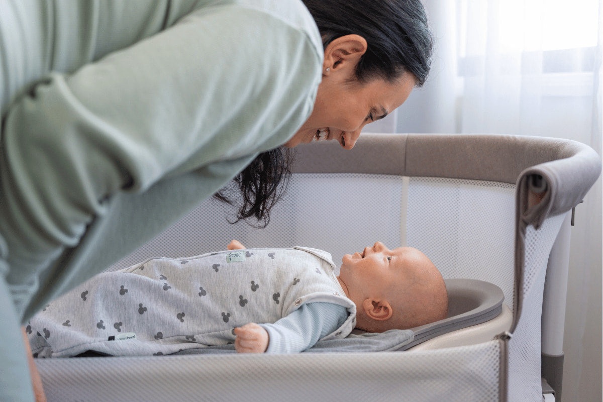 A parent with their baby beside a bassinet