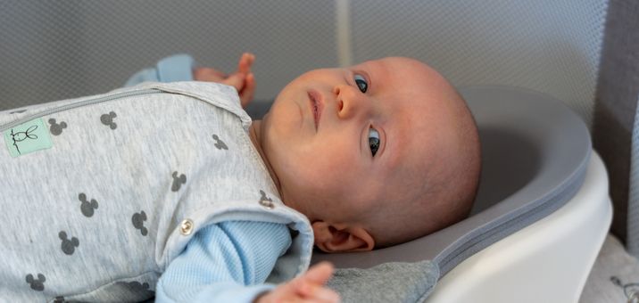A baby lying on his back on the Perfect Noggin, looking up