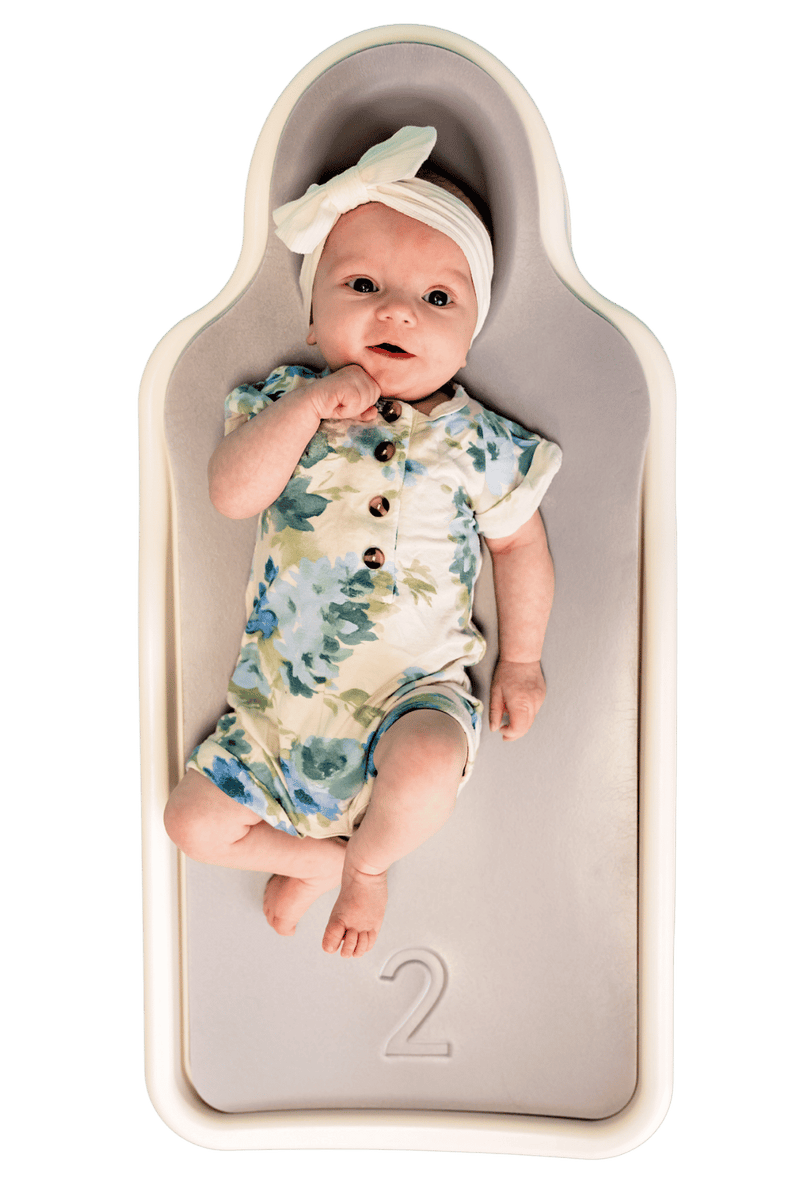 A baby lying on their back on the Perfect Noggin, seen from above